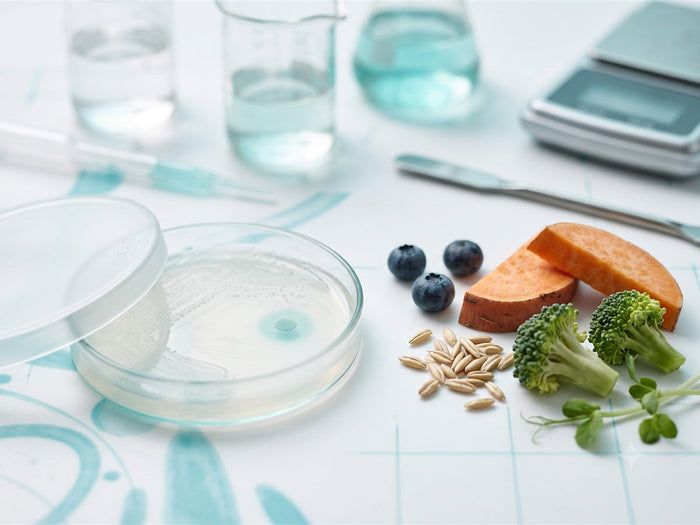 Muestra de laboratorio junto a alimentos, microbiota infantil